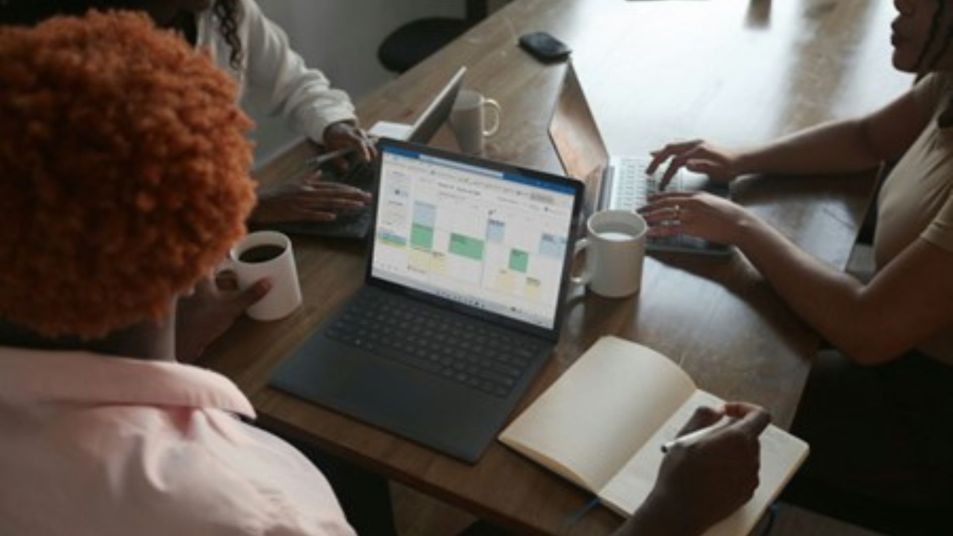 people in meeting with microsoft planner on laptop screen