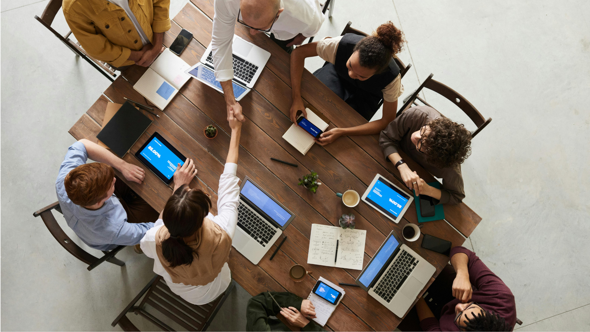 people sitting around a table in a meeting with electronics