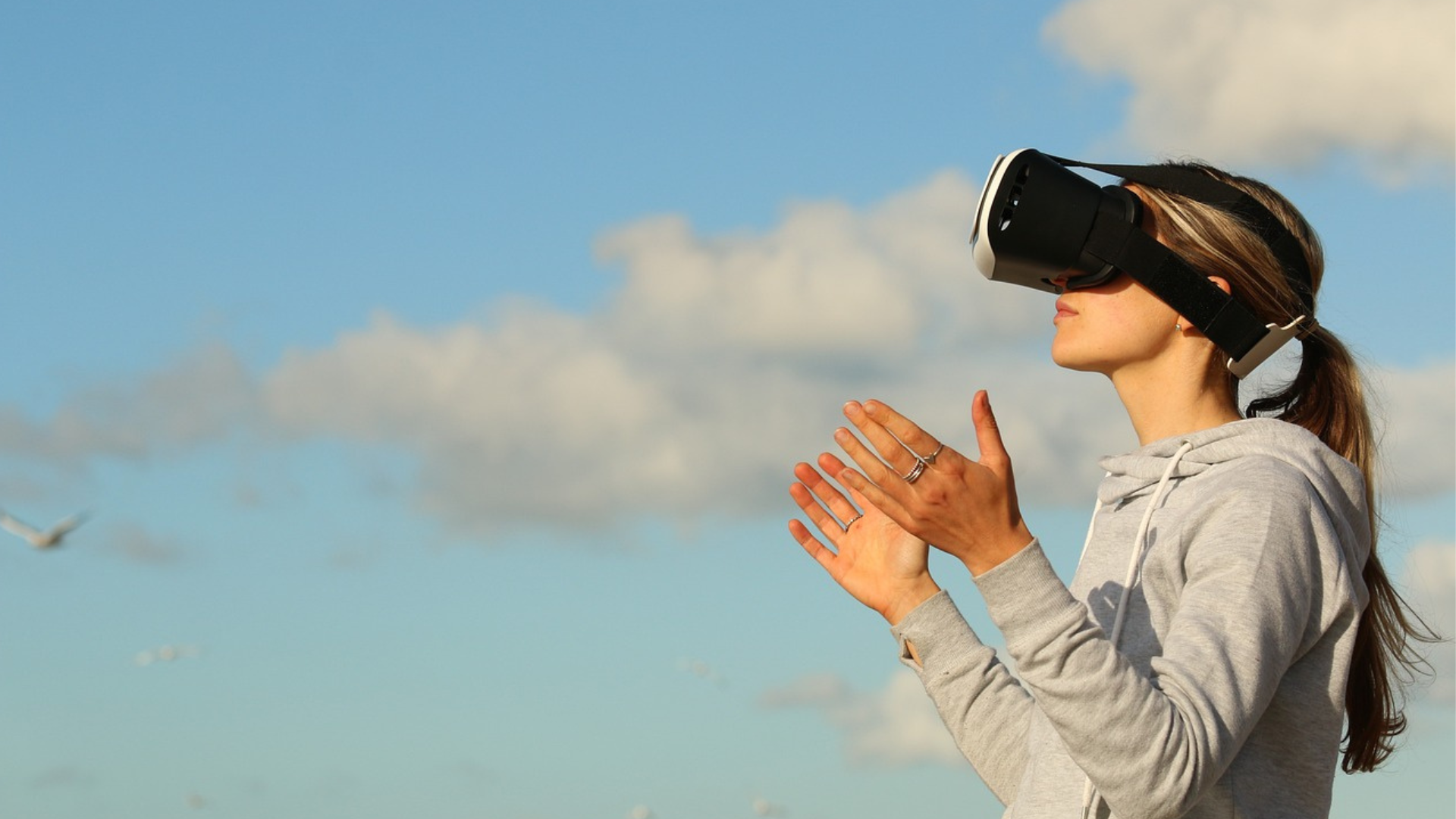 Girl Standing with clouds behind her wearing a VR headset