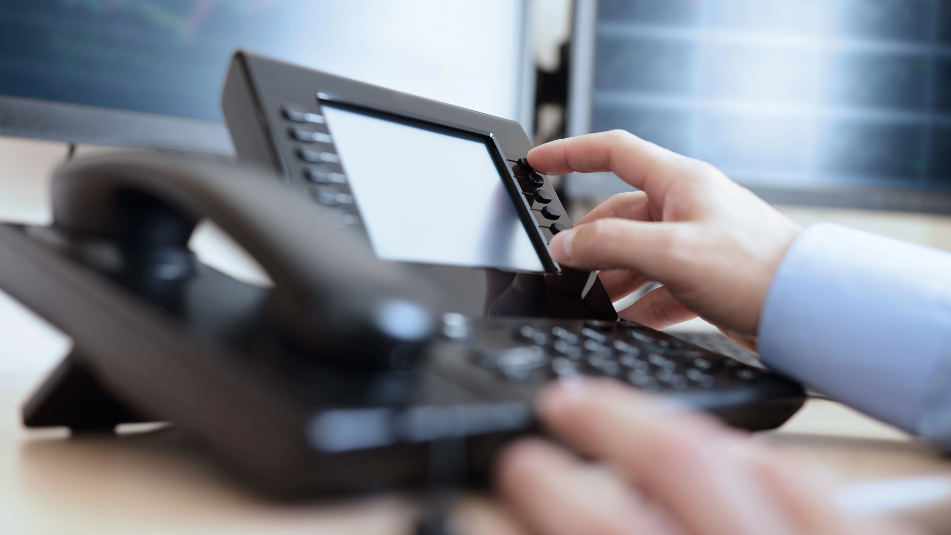 hand on a desk phone pressing buttons